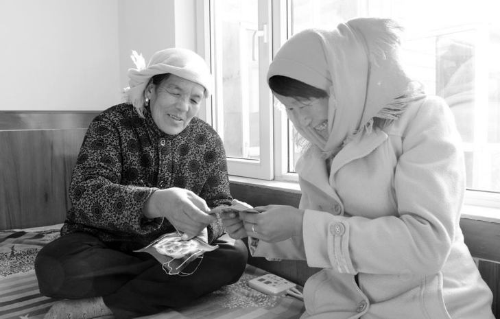 村民坐在干凈舒適的電熱炕上制作土族盤繡